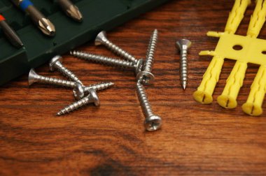 Montajcının çalışma süreci. Koyu bir ahşap yüzeyde vidalar ve plastik kaplamalar. 