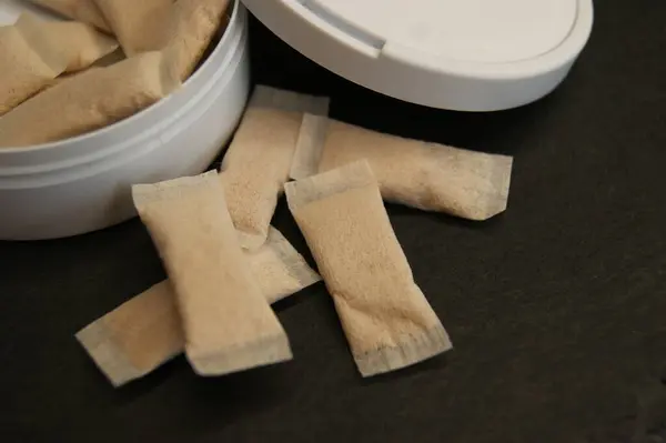 Bir kutu dolusu nikotin torbası. Koyu bir arka planda ambalaj ve nikotin pedleri. 