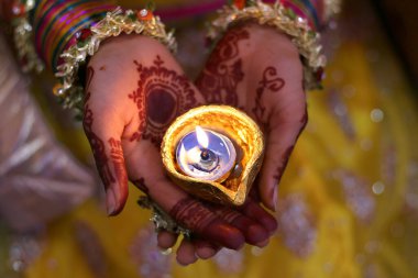 Kadın elleri ve mehendi yanan bir mum tutuyorlar.