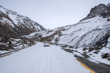 Dağlarda güzel manzarası olan karlı yolda giden araba.