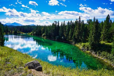 Bulutlar, Kanada 'nın Jasper bölgesindeki Beş Göller Vadisi' nin görkemli göl göllerinin üzerinde açık mavi bir gökyüzünde süzülüyor.