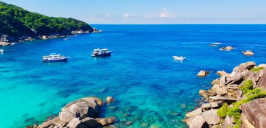 Tayland, Phuket açıklarında Andaman Denizi, Similan Adaları 'ndaki kayalıkların tepesinden ışıltılı gök mavisi sularıyla manzaralı deniz manzarası.