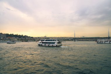 İstanbul, Türkiye 'deki gül rengi bir akşamda İstanbul Boğazı' nın tarihi ve ünlü altın boynuzlu su kanallarında seyir ve turizm tekneleri uçuyor