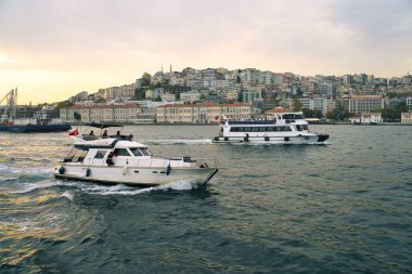 İstanbul, Türkiye 'deki gül rengi bir akşamda İstanbul Boğazı' nın tarihi ve ünlü altın boynuzlu su kanallarında seyir ve turizm tekneleri uçuyor