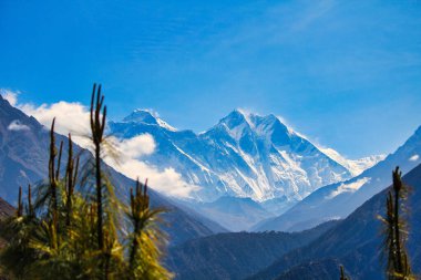 Mount Everest summit is visible against a sunny, bright blue sky above the Nuptse ridge along with Lhotse in this first view that trekkers get of the world's highest peak at Namche Bazaar,Nepal clipart