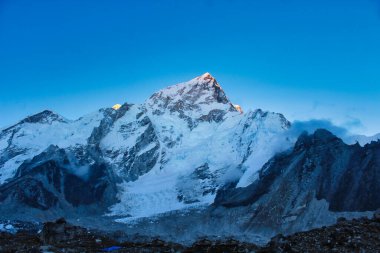 Summits of Nuptse and Everest lit up by the last rays of the setting sun in this tranquil twilight scene from Gorakshep in Nepal clipart