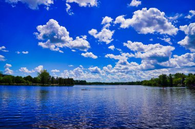 Parlak bir yaz günü Ottawa, Ontario, Kanada 'da, parlak bir Rideau nehrinin üzerindeki bulutlarla masmavi parlak gökyüzü.