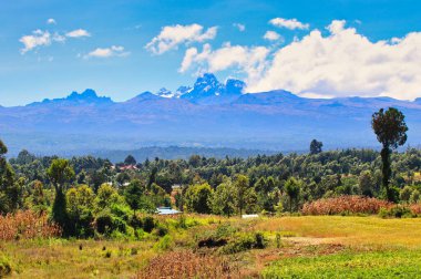 Kenya 'nın en yüksek dağı olan Kenya Dağı' nın 5199 metre yüksekliğindeki manzarası, Kenya 'nın ekvator bölgesindeki Nanyuki bölgesinden görüldüğü gibi sakin ve aydınlık bir kış gününde merkez dağlardan yükseliyor.