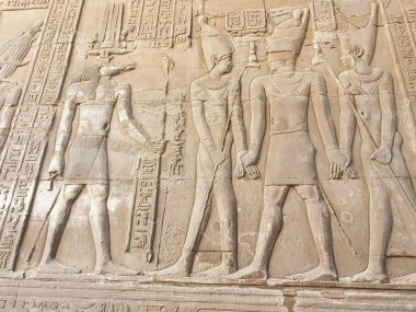 MÖ 2. yüzyılda Ptolemy firavunları tarafından Kom Ombo 'da inşa edilen Sobek ve Haroeris Tapınağı' ndaki timsah başlı tanrıça Sobek 'in önündeki firavun yardım duvarı.