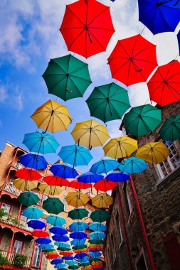 Quebec 'in ikonik Şemsiye Sokağı' nda, Kanada 'nın Quebec eyaletinin başkenti Quebec' teki Petit Champlain alışveriş alanı üzerinde asılı renkli şemsiyeler sergileniyor.