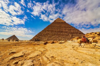 Mısır, Kahire yakınlarındaki Giza platosunda parlak mavi gökyüzü ve turistlerle Büyük Khafre ve Menkaure Piramidinin muhteşem geniş açılı görüntüsü.