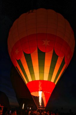 Mısır 'ın Luxor kenti yakınlarındaki şafak öncesi karanlıkta bir Luxor balonu safarisi için balonu sıcak havayla dolduran parlak bir ateş patlaması.