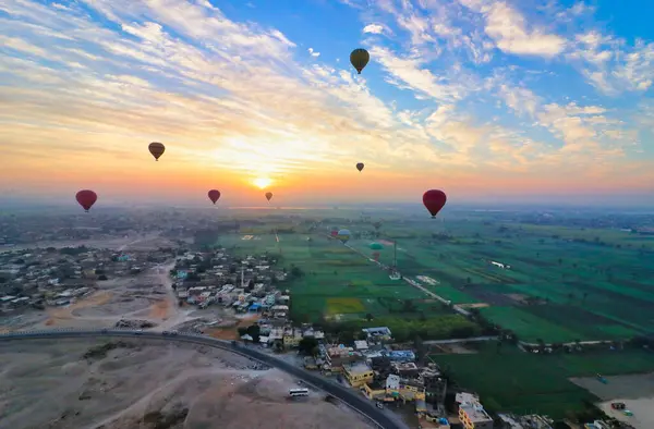 stock image Hot Air balloons rise over the outskirts of Luxor with agricultural fields and archaeological sites offering tourists grand vistas over the town and the desert near Luxor,Egypt