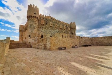 Magnificent view of the top level of the battlements and towers built of yellow sand stone at the Citadel of Qaitbay,built by the Mamluk Sultan Qaitbay in 1479 AD,Pharos Island,Alexandria,Egypt clipart