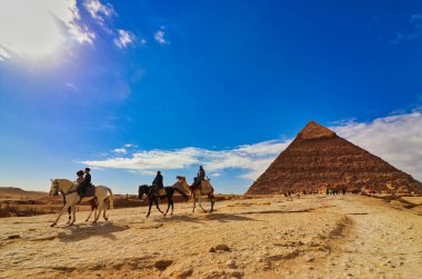 Kahire, Mısır, 29 Aralık 2019 - Büyük Khafre Piramidi, Mısır 'ın Kahire kenti yakınlarında güneşli bir günde deve ve ve atla gezintiye çıkan turistlerle birlikte.