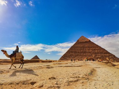 Kahire, Mısır, 29 Aralık 2019 - Büyük Khafre Piramidi, Mısır 'ın Kahire kenti yakınlarında güneşli bir günde, Giza platosunda deve sürüşü yapan turistlerle birlikte.