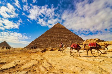 Kahire, Mısır, 29 Aralık 2019 'da Mısır' ın Kahire yakınlarındaki Giza platosunda deve sürüşüne çıkan turistlerle Büyük Khafre ve Menkaure Piramidi 'nin geniş açılı görüntüsü sersemleticiydi.