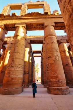 Luxor, Mısır, 3 Ocak 2020 - Karnak 'a gelen ziyaretçi, Karnak tapınağındaki dünyanın en büyük hipotenüs galerisindeki dev ve görkemli sütunlar tarafından cüce gibi gösterildi.