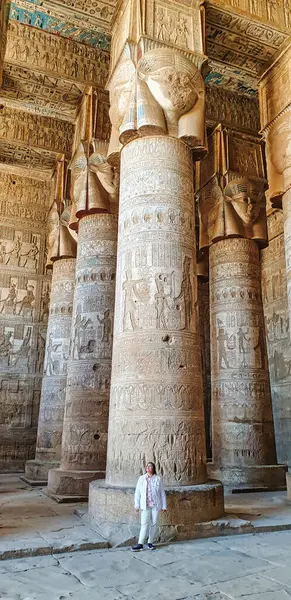 stock image Dendera,Egypt,January 2,2020-A visitor admires the views in the the Great Hypostyle hall with soaring columns topped by carvings of Hathor in the Temple of Dendera between Luxor and Abydos towns,Egypt