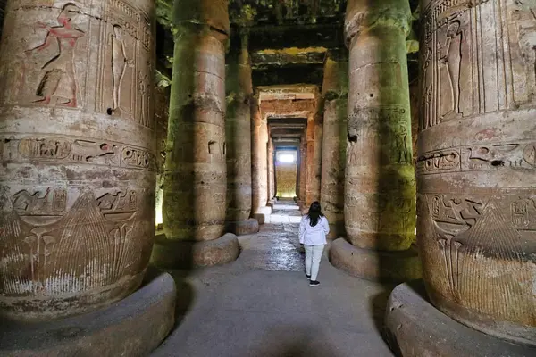 stock image Abydos,Egypt,January 2,2020-A visitor enjoys the views of the atmospheric hypostyle gallery leading to the seven chambers in the Temple of Seti built in 13th century BC by the Pharoah Seti I