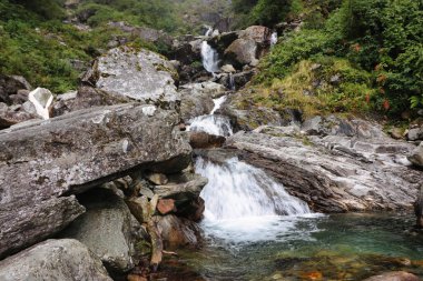 Nepal 'in Chhetra Khola köyü yakınlarındaki muson aylarında alçak Himalayalar' ı noktalayan yoğun bulut ormanlarından dağ dereleri taşar.