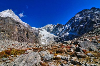 Hikers pass close to the icefall of Kyashar Peak,6769 meters as seen close to Khare village on route to Base camp of Mera Peak,6476 meter high peak in the Khumbu Himalayas,Nepal clipart