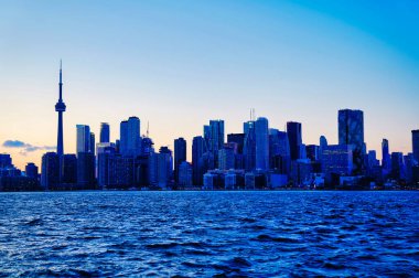 Toronto City Skyline sembolik CN Kulesi ve finans bölgesindeki diğer önemli binalarıyla akşam saatlerinde Toronto, Ontario, Kanada 'da Ontario Gölü' ndeki Ward 's Island feribotundan görüldü.