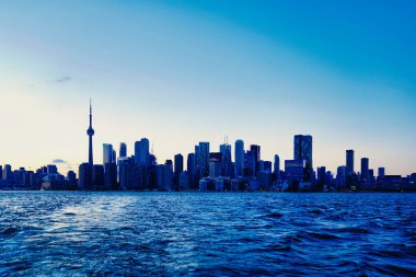 Toronto City Skyline sembolik CN Kulesi ve finans bölgesindeki diğer önemli binalarıyla akşam saatlerinde Toronto, Ontario, Kanada 'da Ontario Gölü' ndeki Ward 's Island feribotundan görüldü.
