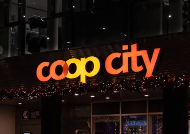 Basel, İsviçre - 23 Aralık 2024: Basel 'deki bir mağaza girişinin üzerinde aydınlatılmış Coop City logosu, Noel ışıklarıyla süslenmiş