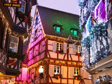 Colmar, Fransa - 26 Aralık 2024: Fransa 'nın Colmar kentinde renkli Noel ışıklarıyla süslenmiş geleneksel yarı keresteli evler