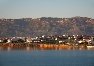 Pag Adası 'ndaki Povljana sahil köyünün üzerinde ılık bir alacakaranlık süzülüyor. Beyaz evleri Adriyatik' te yansıyor..