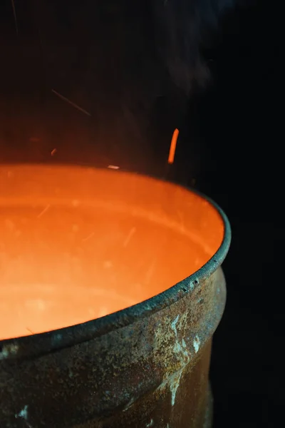 stock image fire burning inside a metal barrel at night