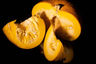 Sarı balkabağı dilimlenmiş siyah arkaplan.