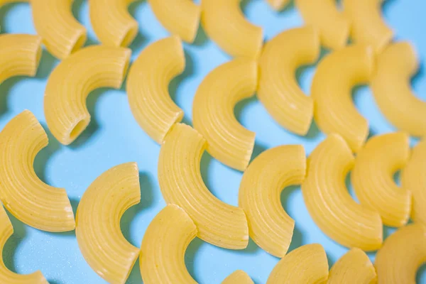Wheat pasta in the shape of a horn on a blue background.