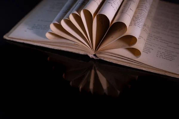 Old book with folded pages in the form of flowers. Black background.