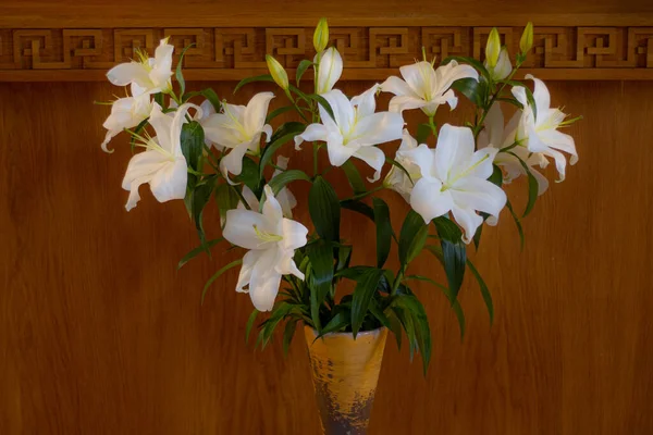 Flowers in a lily vase on a table in a church.