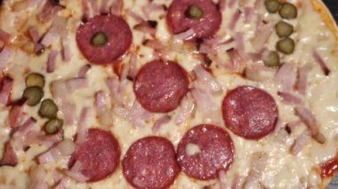 Pizza salamı, jambon ve peynir. Peynirli, taze pişmiş salamlı pizza. Çok güzel dönüyor. Video klipler. Pizza gülümsemesi..