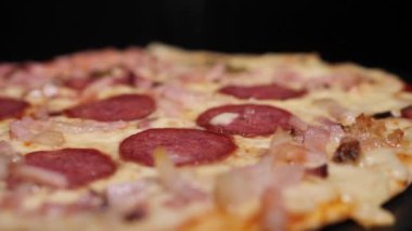 Pizza salamı, jambon ve peynir. Peynirli, taze pişmiş salamlı pizza. Çok güzel dönüyor. Video klipler. Pizza gülümsemesi..