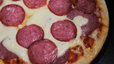 Pizza üzerine karabiber serpintisi, baharatlı. Pizza salamı, jambon, peynir. Peynirli, taze pişmiş salamlı pizza. Çok güzel dönüyor. Video klibi. Pizza gülümsemesi..