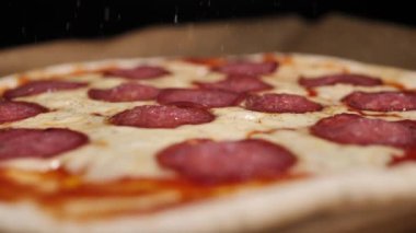 Pizza üzerine karabiber serpintisi, baharatlı. Pizza salamı, jambon, peynir. Peynirli, taze pişmiş salamlı pizza. Çok güzel dönüyor. Video klibi. Pizza gülümsemesi..