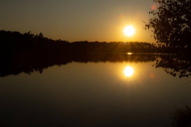 Günbatımı güneşi gölün suyuna yansıyor. Gölde iki güneş, altın güller. İyi akşamlar..