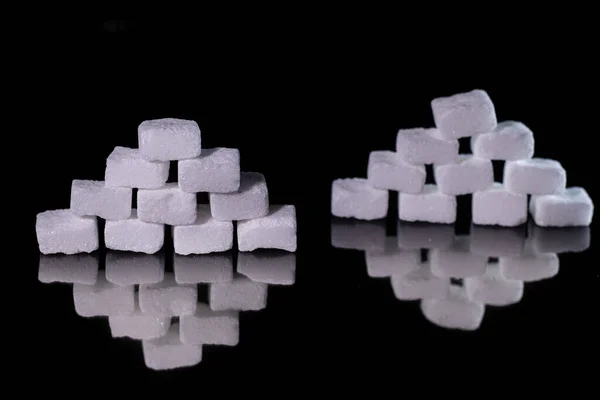 Squares of sugar cubes on a black background. Diabetes. Sugar disease.
