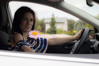 Elinde çiçek olan bir kadın onu burnuna koyar, gözleri kapalı mutlu bir şekilde. Tatil eğlencesi.