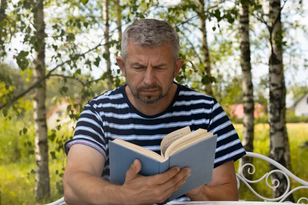 Ένας Άντρας Διαβάζει Ένα Βιβλίο Έξω Στο Τραπέζι Άνθρωπος Ξεκουράζεται — Φωτογραφία Αρχείου