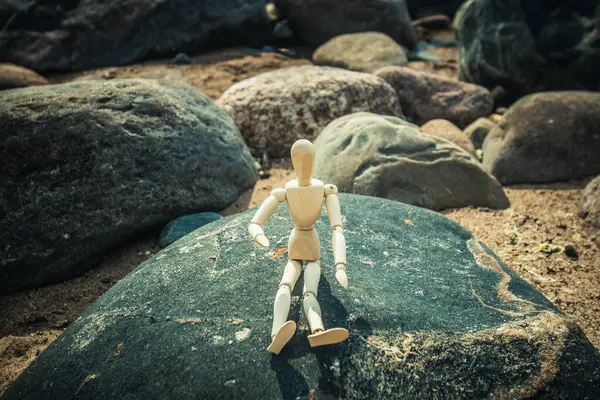 stock image Silhouette of a wooden man on the rocks on the seashore. A silhouette of a wooden man was found by the sea.