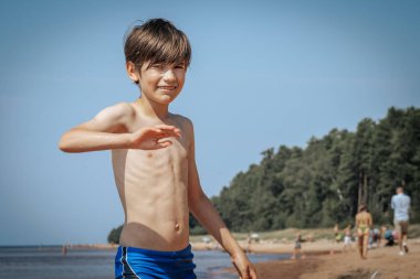 Deniz kenarında el sallayan bir çocuk, yaz tatili. Yumuşak seçici odak.