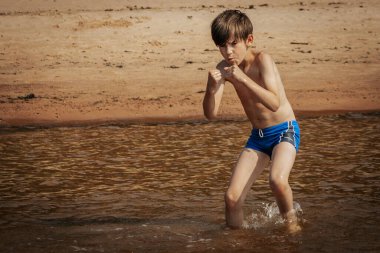 Deniz kenarında egzersiz yapan bir çocuk, yaz tatili. Yumuşak seçici odak.