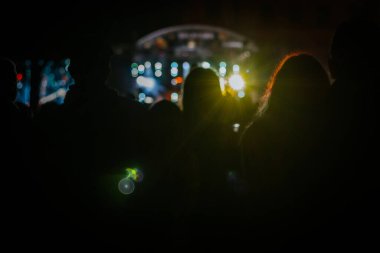 Bayram kutlaması için ışıkları olan konser sahnesi. İnsan silueti. Arka plan bulanık. Soyut renk odak noktasında yanıp sönüyor. Bulanık peri ışıkları. Yumuşak seçici odak.