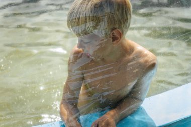 Evinin havuzunda, su damlaları olan koruyucu bir filmin önünde..