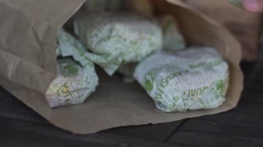 Bir çocuk eliyle paketten hamburger alır. Yumuşak seçici odaklanma. Video klipleri.